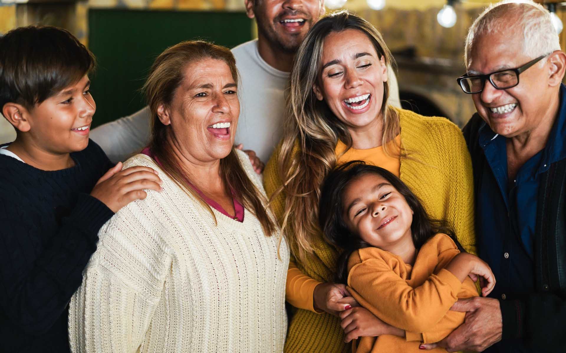 Familia reunida sonriendo y abrazándose.